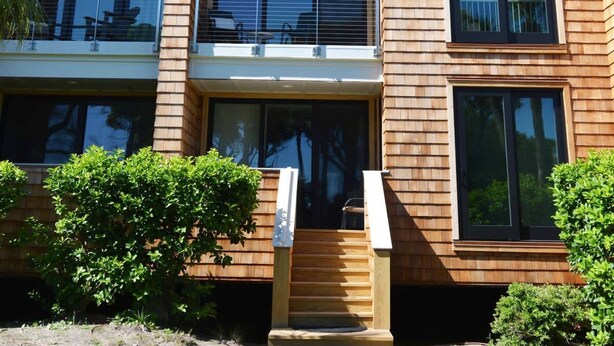 Un immeuble à plusieurs étages doté de balcons, de grandes fenêtres et d’une façade en bois.