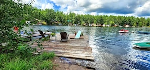 A wooden dock extending into a lake with boats, surrounded by trees and houses in the background. - 3 Epic Stays on Private Island (Brantingham)