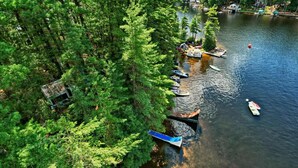 A lakeside area with several boats docked along the shore, surrounded by dense green trees. - 3 Epic Stays on Private Island (Brantingham)