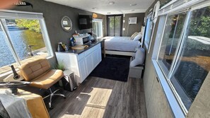 A compact boat interior with a kitchenette, a small seating area, a bed, and large windows offering views of the water. - 3 Epic Stays on Private Island (Brantingham)