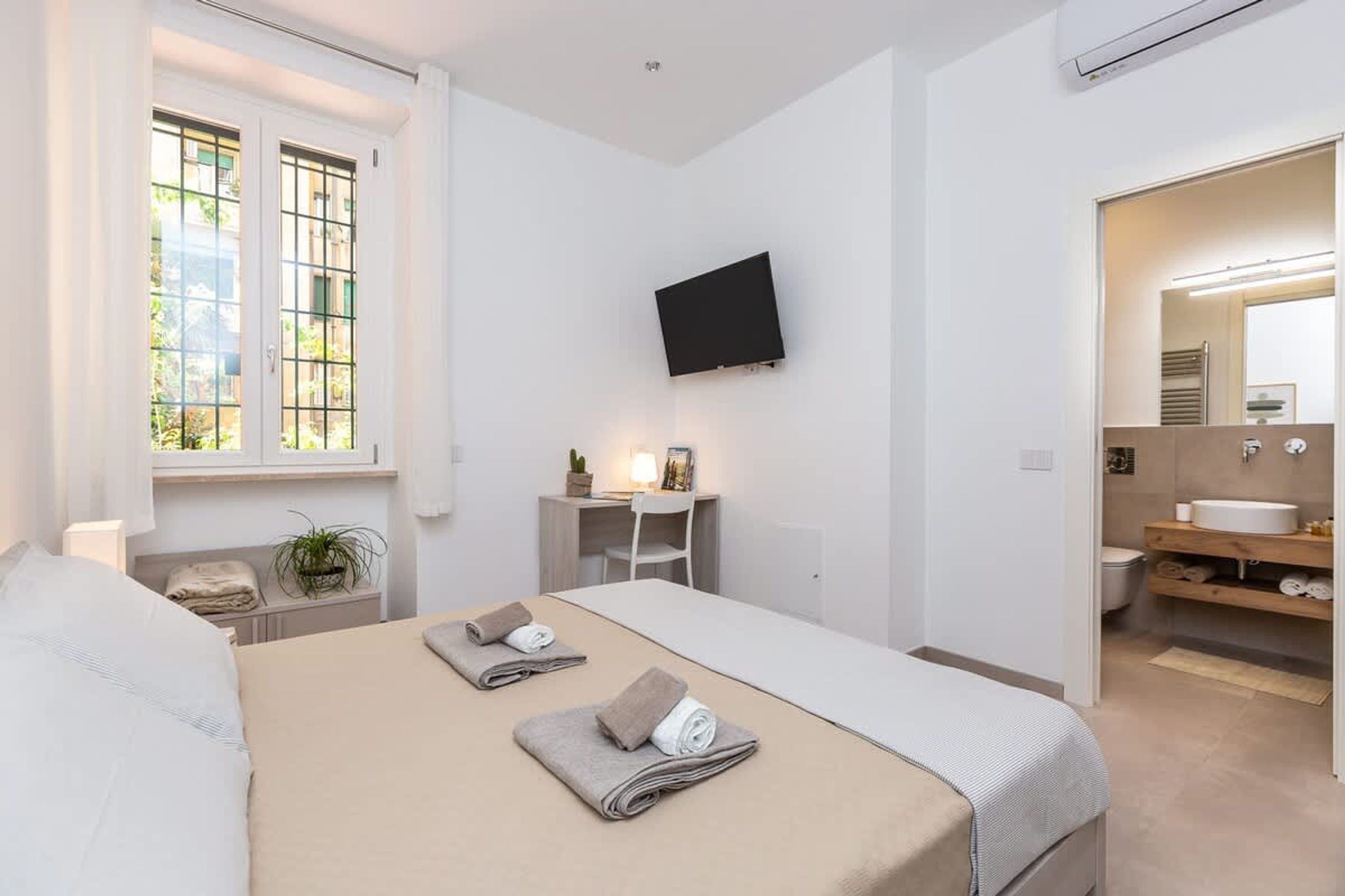 Habitació d'hotel amb llit, escriptori, televisió i bany amb rentatge i mirall.