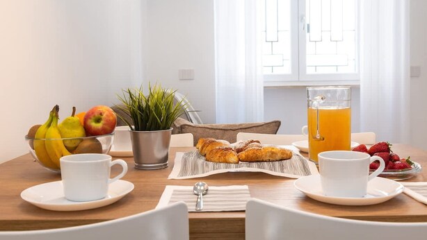 A breakfast table with fruits, pastries, and a glass of orange juice. - Colosseum Holidays - Marco Aurelio (Rome)