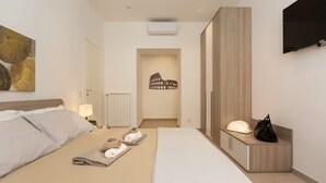 A modern hotel room with a large bed, a bedside table with a lamp, a wardrobe, and a flat-screen TV mounted on the wall. - Colosseum Holidays - Marco Aurelio (Rome)