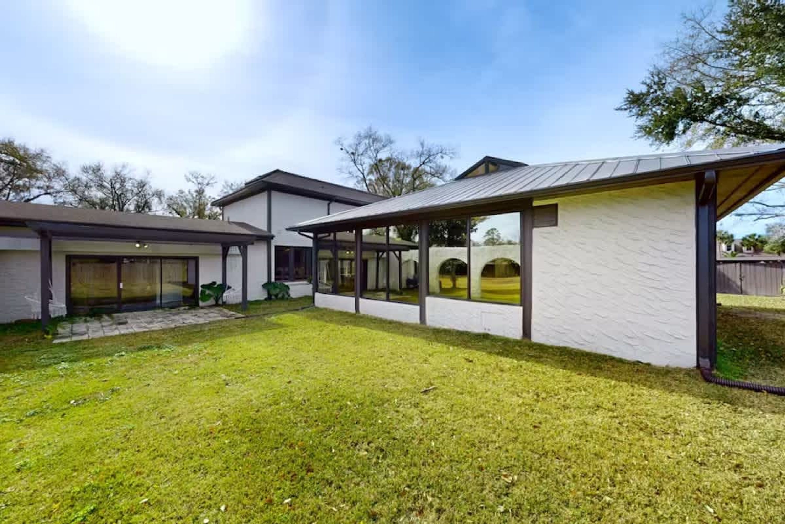 A modern house with a covered patio, a fenced yard, and a garage.
