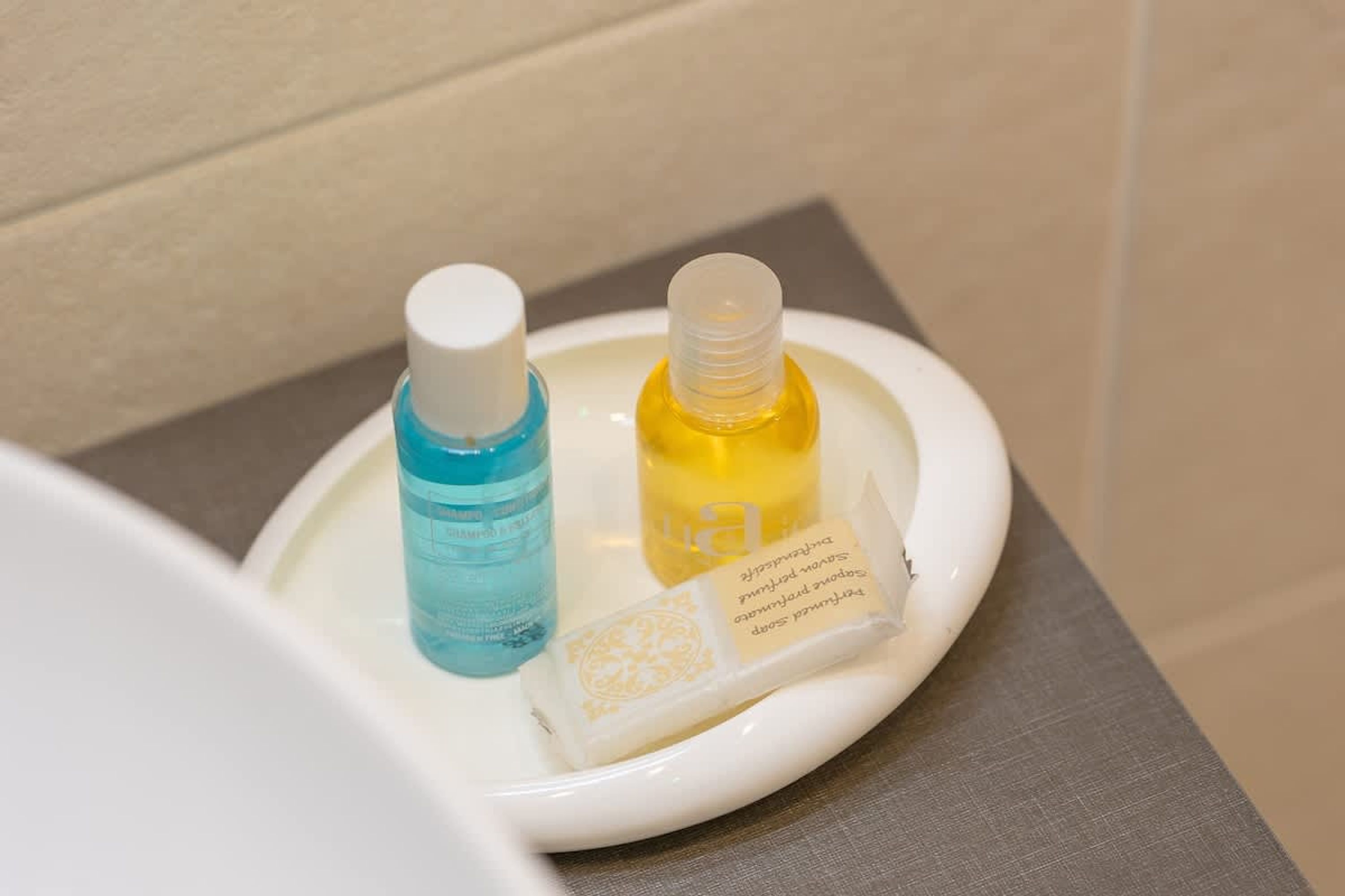 A bathroom sink with two bottles of liquid soap and a bar of soap.