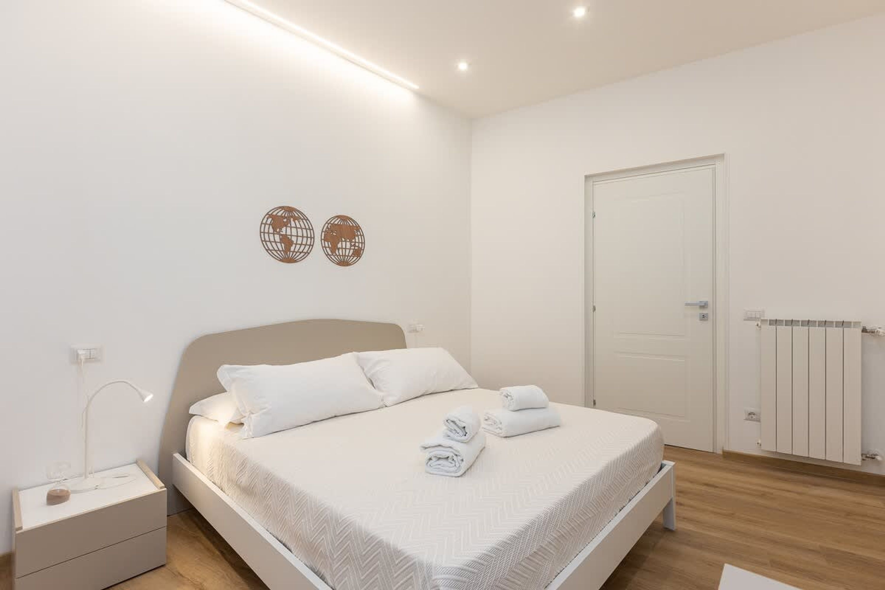 A bedroom with a bed, bedside table, wall decor, and a door.