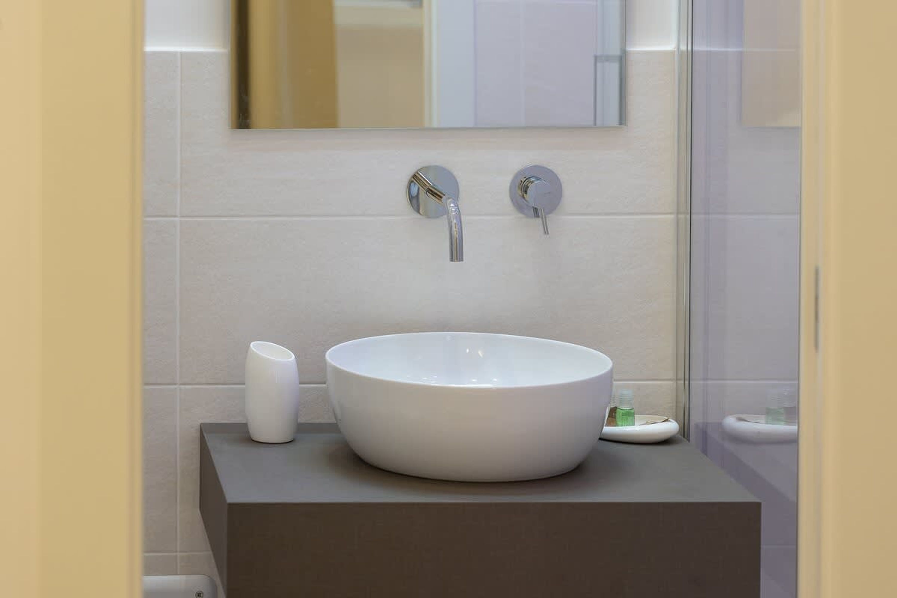 Een badkamer met een wit wastafelmeubel, een spiegel en een douchecabine van glas.