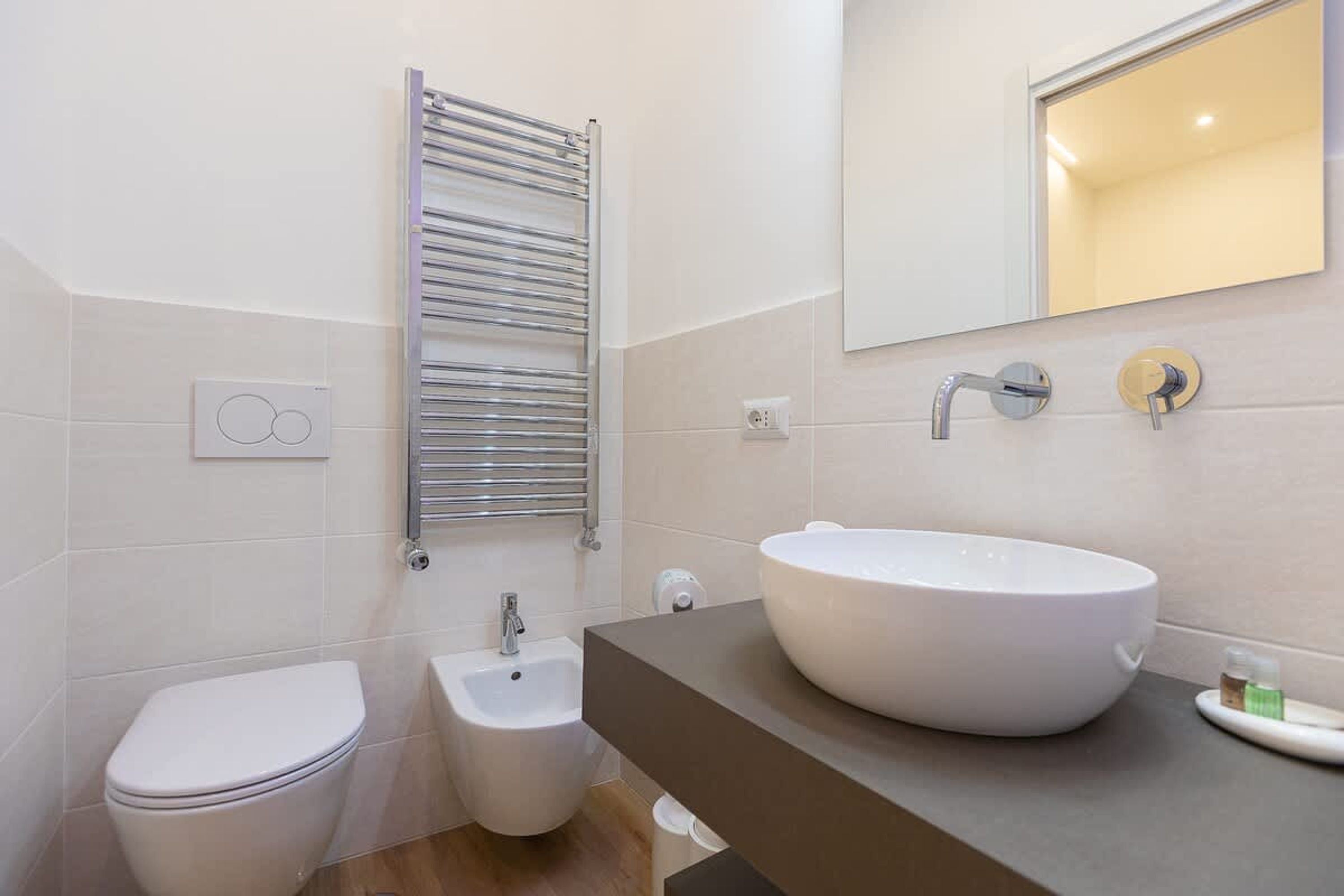 Un bagno moderno con un water bianco, un bidet, un lavandino ampio in bianco e un porta asciugamani.