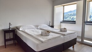 A bedroom with a large bed, a nightstand, a lamp, and a sliding glass door leading to a balcony with a view of the outdoors. - Dream View Apt With Homecinema Netflix Loggia (Kriens)