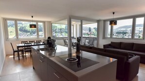 A modern kitchen with a central island, dining area, and a sofa. - Dream View Apt With Homecinema Netflix Loggia (Kriens)