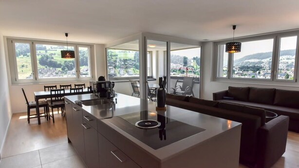 A modern kitchen with a central island, dining area, and a sofa. - Dream View Apt With Homecinema Netflix Loggia (Kriens)