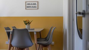 Un comedor con una mesa y sillas, un jarrón con flores y un cartel en la pared.