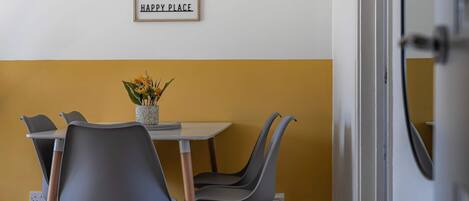Un comedor con una mesa y sillas, un jarrón con flores y un cartel en la pared.