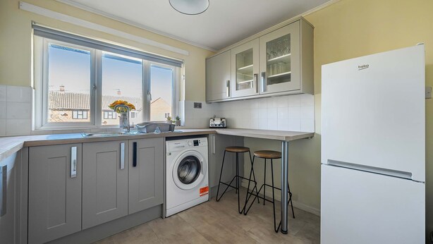 Una cocina moderna con lavadora, taburetes de bar y refrigerador.