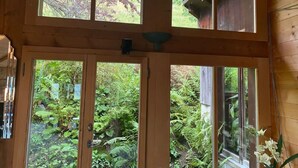 Un intérieur en bois avec une grande porte vitrée donnant sur un jardin luxuriant.