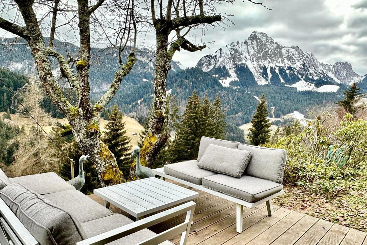 A deck with outdoor furniture overlooking a mountainous landscape.