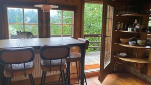 Un intérieur rustique en bois, avec une table à manger, des chaises et une étagère contenant des ustensiles de cuisine.