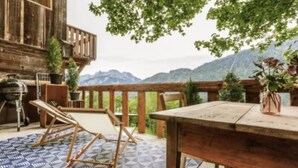 A wooden deck with a table and chairs, a grill, and potted plants. - Heidi Chalet - Panoramic View - Modern Part (Rossiniere)