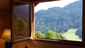 A room with a large window offering a view of a forested mountain. - Heidi Chalet - Panoramic View - Modern Part (Rossiniere)