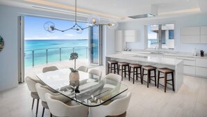 A modern kitchen with a large island, bar stools, and a view of the ocean. - Oceanfront Penthouse and Patio at ONE Cable Beach (Nassau)