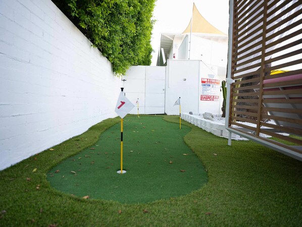 A small, enclosed area with artificial grass, a white wall, and a wooden fence. - Standard Room, 2 Queen Beds, Kitchenette, Garden View (Palm Springs)