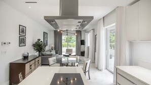 Una cucina moderna con isola centrale, zona pranzo con tavolo rotondo e vista all'esterno tramite ampie finestre.