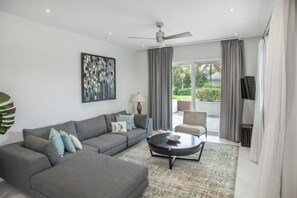 A modern living room with a grey sectional sofa, a round coffee table, and a ceiling fan.