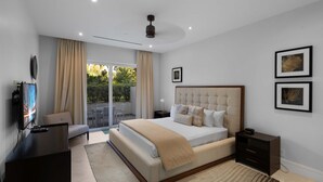 Un dormitorio moderno con una cama grande, televisor y vistas al balcón.
