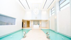 Un vestíbulo de hotel con una recepción, zona de piscina y una araña.