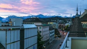 A cityscape with buildings, a road, and snow-capped mountains in the background. - Modern Flat w Netflix Balcony top Location (Lucerne)