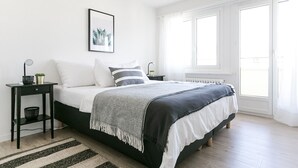 A bedroom with a bed, a bedside table, a floor lamp, a framed picture on the wall, and a window with curtains. - Lucern 2-br Flat w Netflix Top Location (Lucerne)