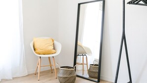 A room with a white chair, a large mirror, and a black hanger on a wall. - Lucern 2-br Flat w Netflix Top Location (Lucerne)