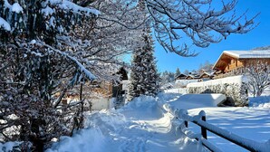 A snow-covered pathway leading to a wooden lodge with a clear blue sky. - Le Petite Chalet in Rougemont (Rougemont)