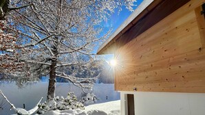 A wooden cabin with a clear view of the surrounding snowy landscape and a tree with snow-covered branches. - Le Petite Chalet in Rougemont (Rougemont)