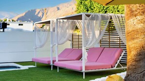Un espacio de descanso al aire libre cubierto con un toldo, una piscina y un cactus.