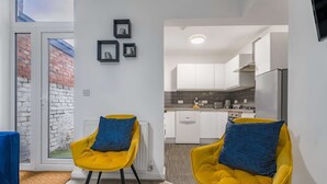 Un apartamento moderno con dos sillas amarillas, una mesa de comedor y una cocina con armarios blancos.
