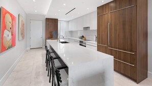 A modern kitchen with a large island, wooden cabinets, and a white countertop. - 2 Bed Ocean View Condo at ONE Cable Beach (Nassau)