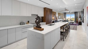 A modern kitchen with a marble island, white cabinetry, and a large window offering a view. - 2 Bed Ocean View Condo at ONE Cable Beach (Nassau)