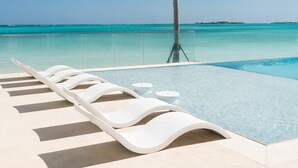 A poolside area with lounge chairs and a view of the ocean. - 2 Bed Ocean View Condo at ONE Cable Beach (Nassau)