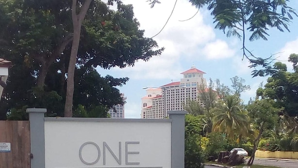 Señal de 'ONE Cable-Beach' con vista despejada del entorno, incluyendo una carretera y un edificio al fondo.