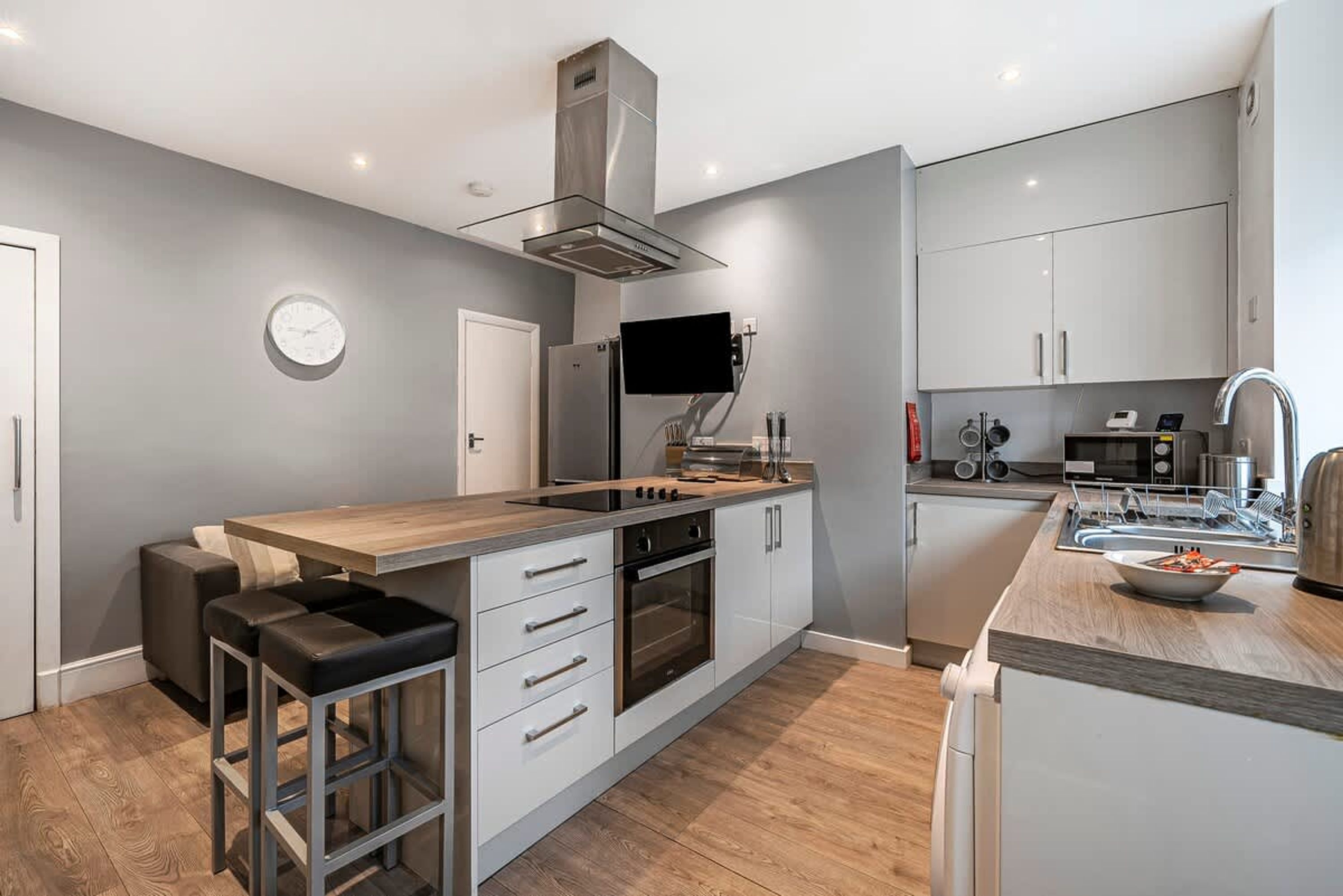 A modern kitchen with a central island, built-in oven, and stainless steel appliances.