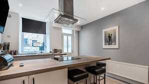 A modern kitchen with a central island, bar stools, a window with a view, and a framed picture on the wall.