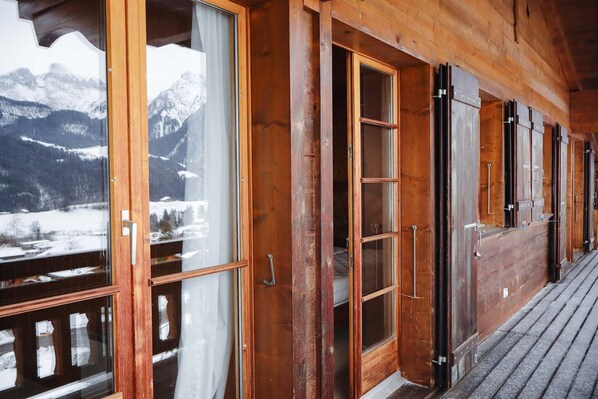 A wooden building with large windows and doors, offering views of snow-covered mountains.