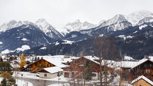 Un pueblo de montaña con casas de madera, un paisaje cubierto de nieve y una vista despejada de las montañas circundantes.