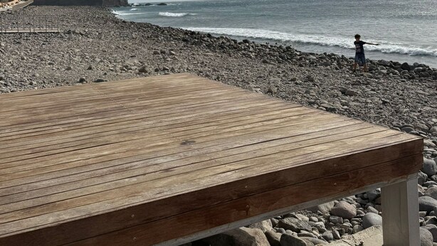 A wooden bench at a rocky beach with a person in the distance. - 4BR Heaven Close to Nature and Ocean in Quiet Setting (Agaete)