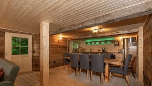 A wooden interior with a dining area, wooden walls, and a kitchen with a green-lit backsplash. - Alps Chalet for Big Group With Sauna Yoga Terrace (Rossiniere)