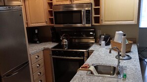 Une cuisine dotée de meubles en bois, d’appareils électroménagers en acier inoxydable et d’un plan de travail en granit.