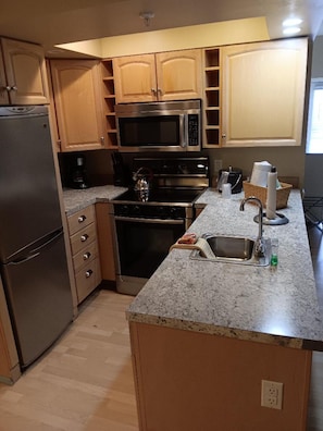 A kitchen with wooden cabinets, stainless steel appliances, and a granite countertop.