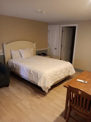 A bedroom with a bed, a wooden table, a chair, and a wardrobe.