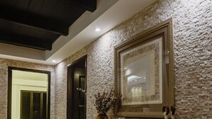 Una hall con una parete in pietra, un tavolo consolle in legno e un quadro incorniciato.